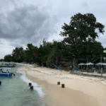 Coastal view of gili air harbour with traditional boats, clear turquoise water, and beachfront area near the main arrival point on Gili Air island.