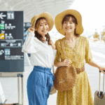 Two happy travelers with luggage at the airport, representing the journey and excitement of booking a ticket to Bali.