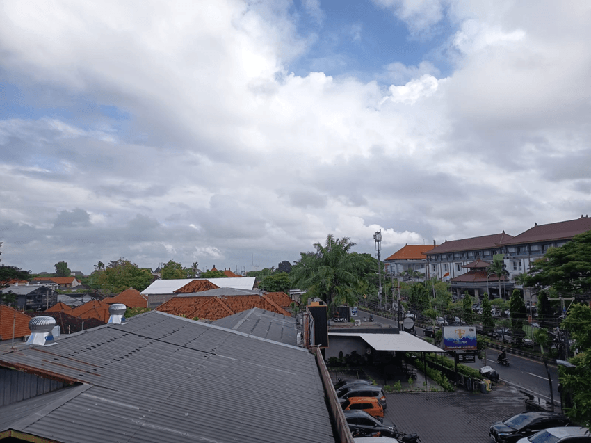 Cloudy sky and urban landscape in Bali during the rainy transition season, showing bali current weather may 2026 with humid tropical conditions and overcast clouds.