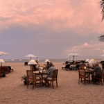Best time to visit Bali featuring a tropical beach dinner, golden sandy beach, calm ocean, and colorful sunset during Bali's dry season.
