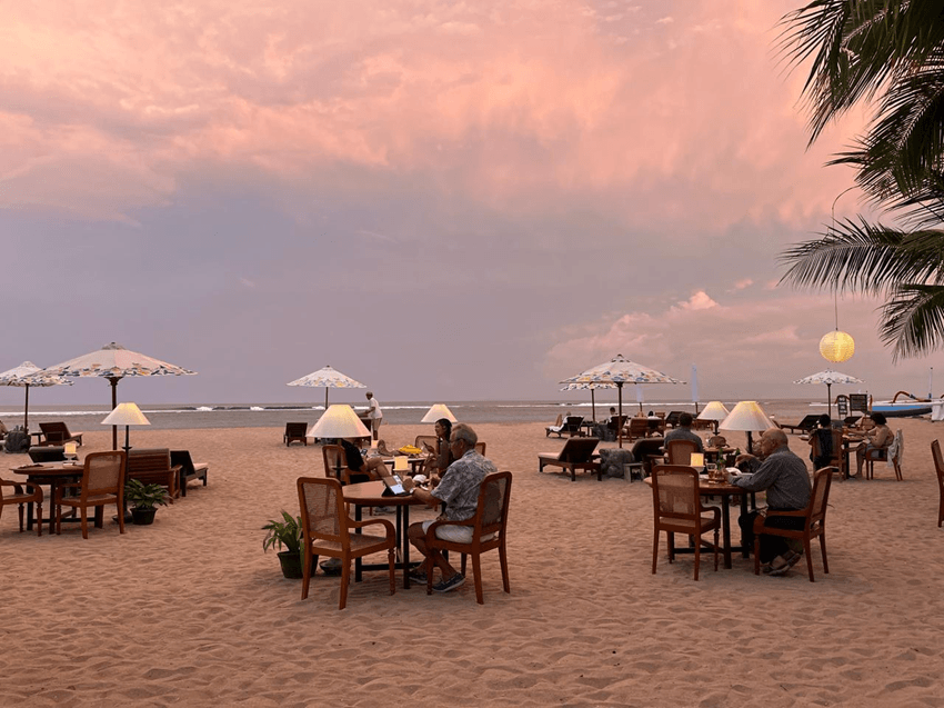 Best time to visit Bali featuring a tropical beach dinner, golden sandy beach, calm ocean, and colorful sunset during Bali's dry season.