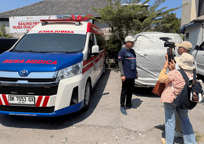 Operational Director PT Nusa Medica Assistama dr. I Gde Yudha Kurniawan during a media interview beside a Nusa Medica ambulance.