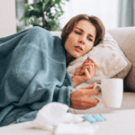 What to Do If You Get Sick in Bali – a sick traveler resting on a sofa while checking her temperature.