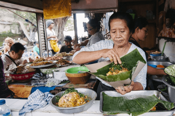 What to Know About Eating Street Food in Bali, featuring a local food vendor preparing traditional Balinese food at a street stall.